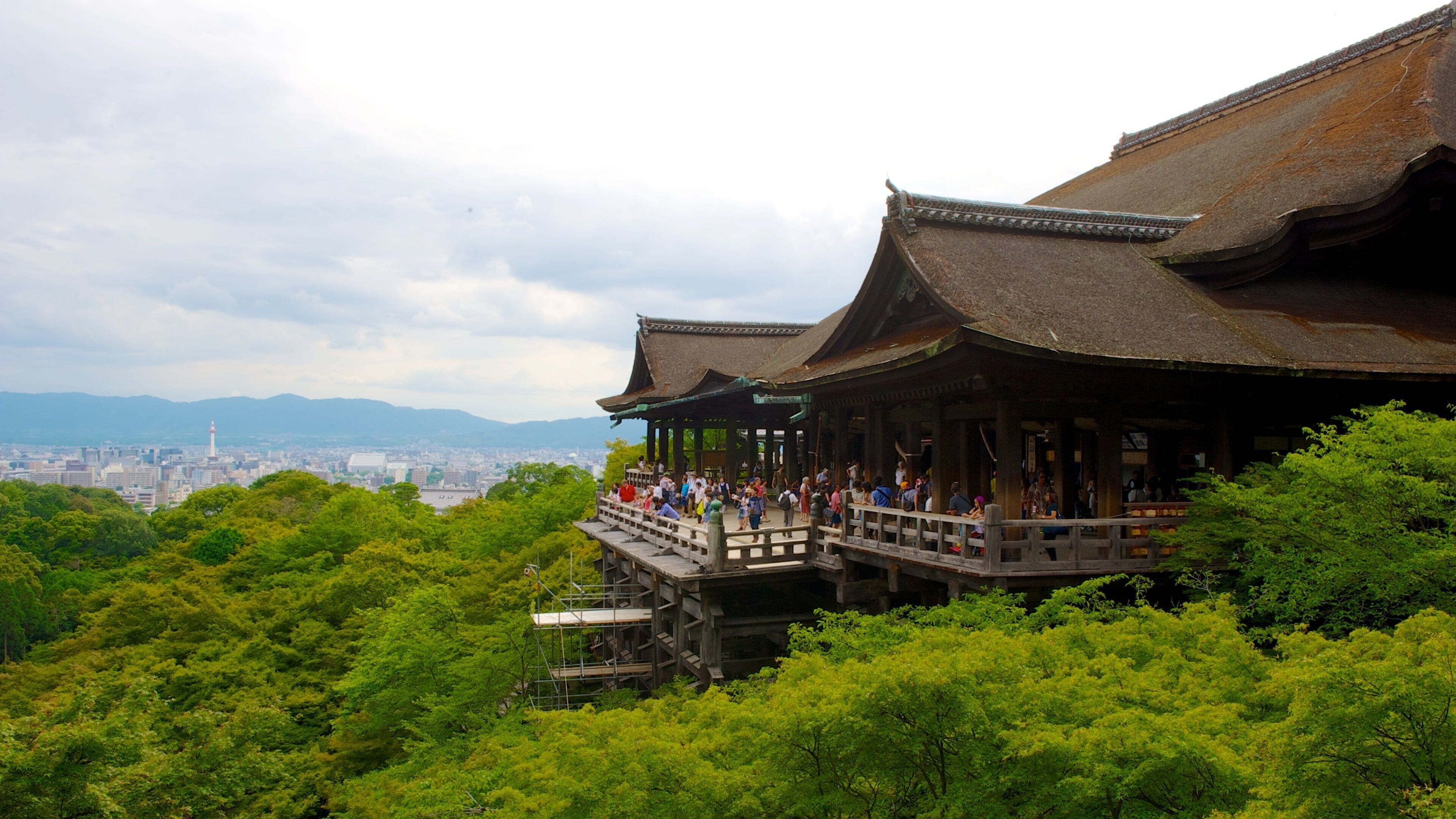 A traditional Japanese building with a wooden structure and a view of a cityscape in the background.