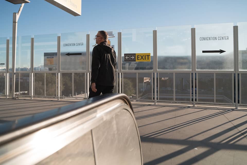 Una persona de pie cerca de una barrera de vidrio con señales direccionales que indican 'Convention Center' y 'Exit'.