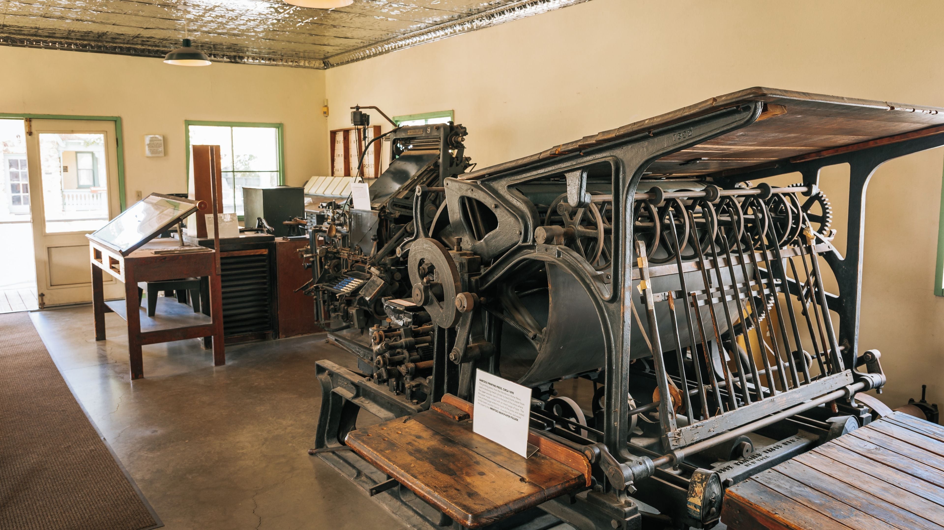 An old printing press with a wooden table and a sign.