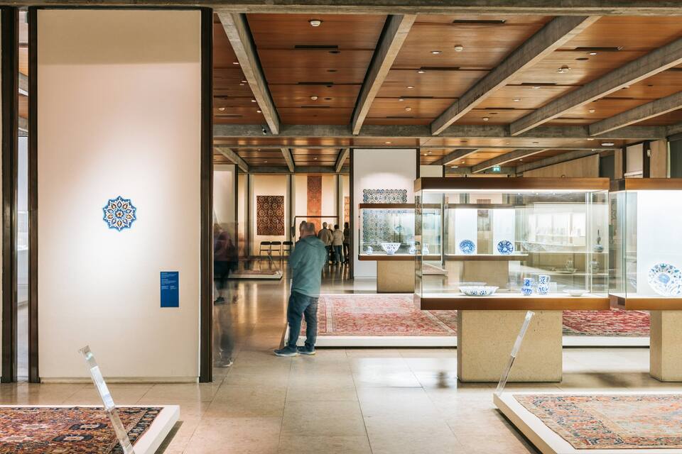 Un espacio interior con vigas de madera, vitrinas de cristal y alfombras estampadas.
