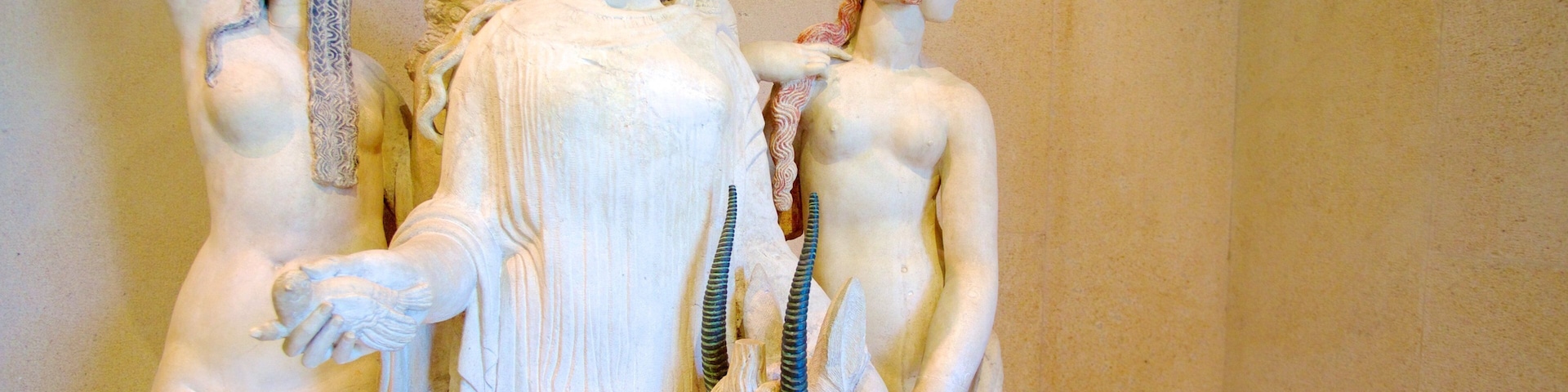 Uma escultura em mármore de uma mulher segurando uma criança, com outra figura ao fundo.