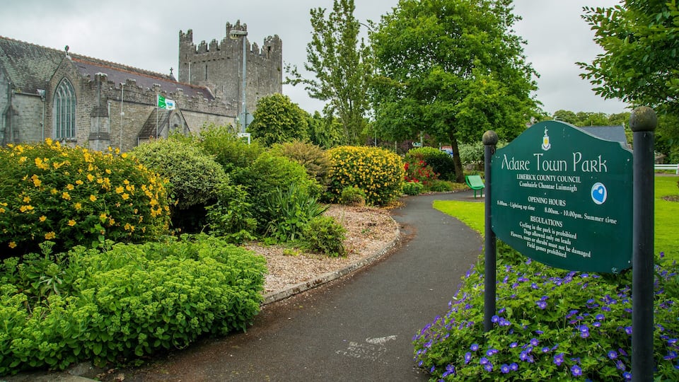 A park sign, lush greenery, and a historic building.