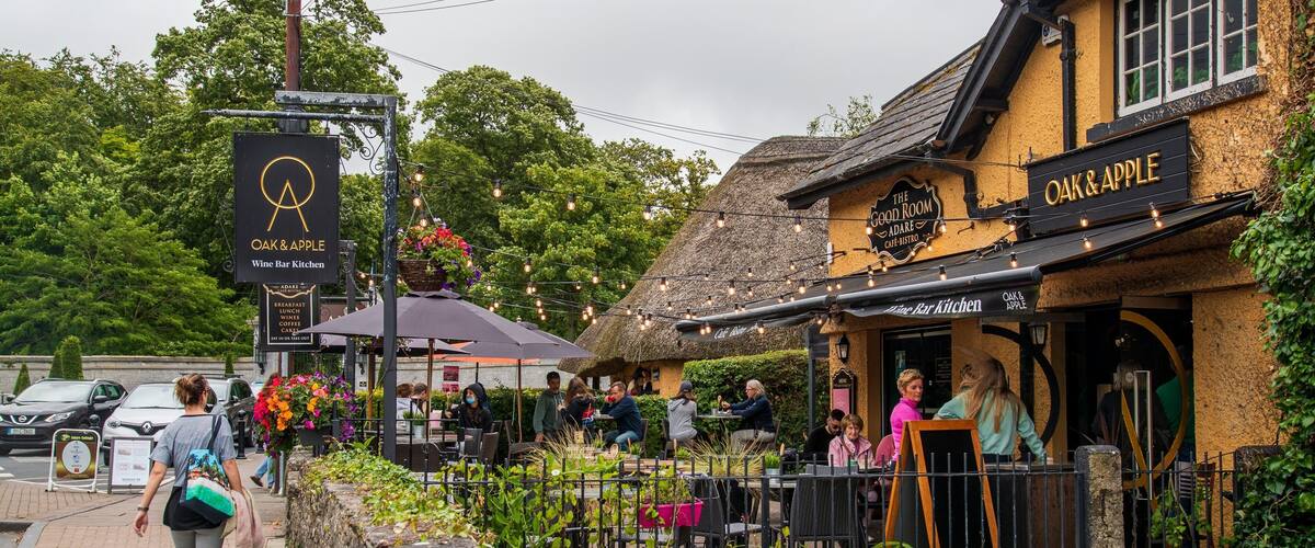 A quaint café with a thatched roof and outdoor seating, surrounded by lush greenery.
