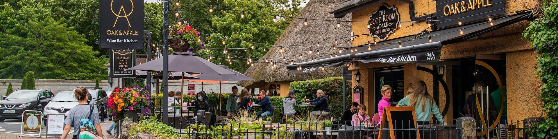 A quaint café with a thatched roof and outdoor seating, surrounded by lush greenery.