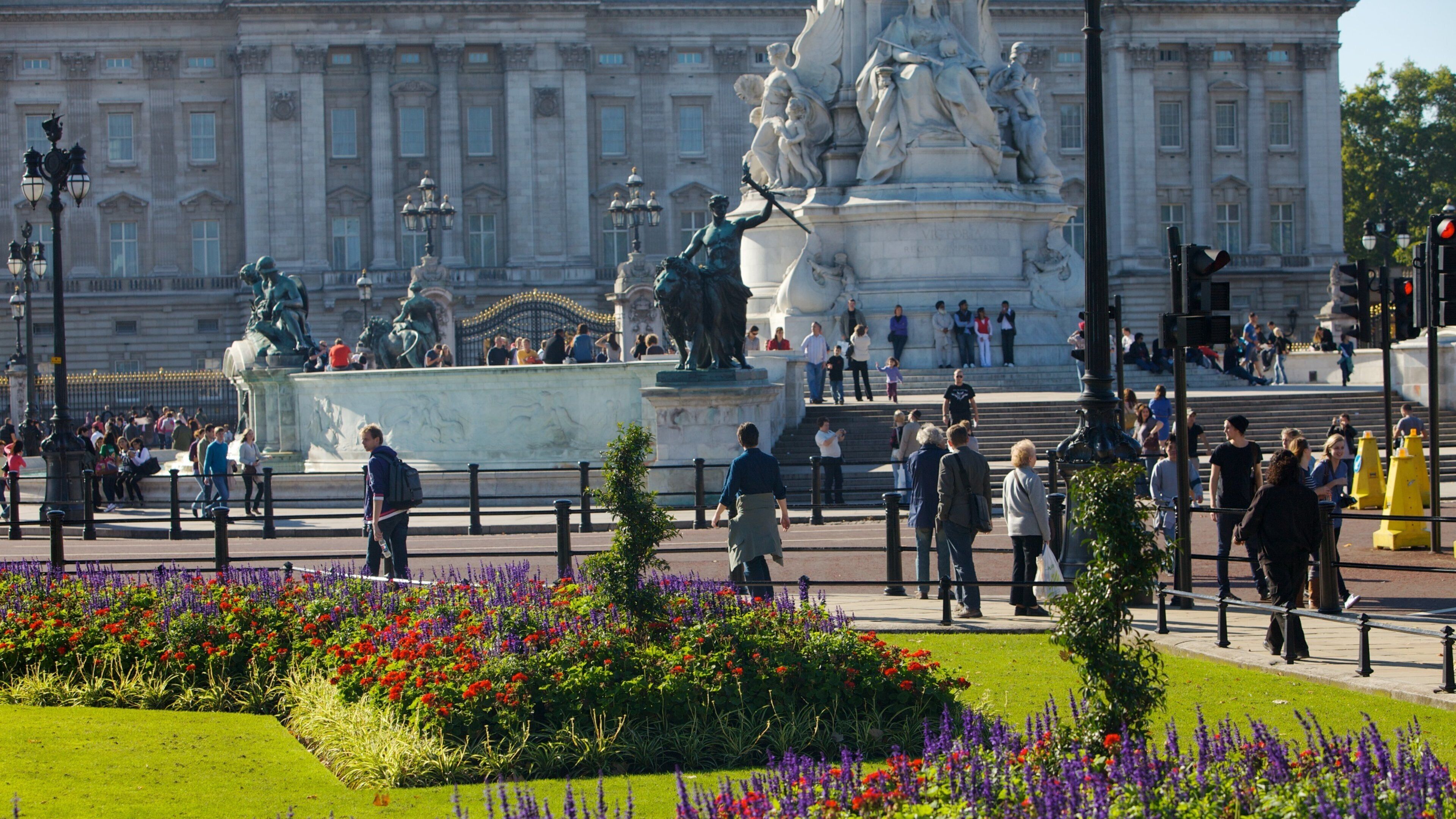 Visitors explore Buckingham Palace gardens while admiring the iconic architecture in London, England during a sunny day