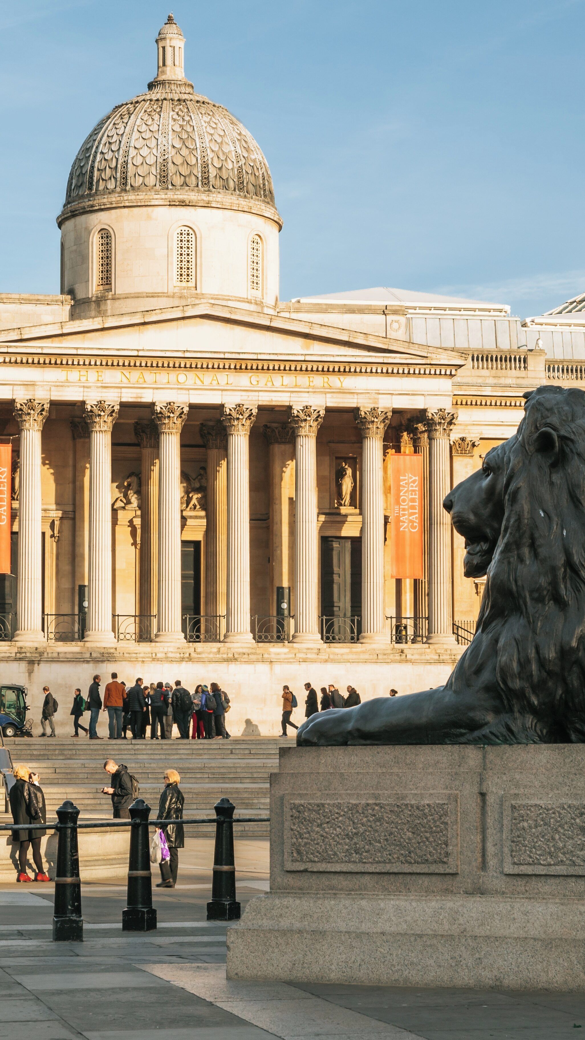 Exploring the National Gallery in Soho, London, with visitors admiring art and architecture on a sunny day