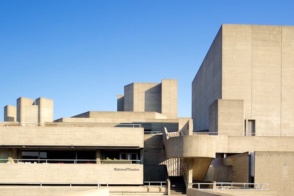 Een modern architectonisch gebouw met een plat dak en een bord waarop 'National Theatre' staat.