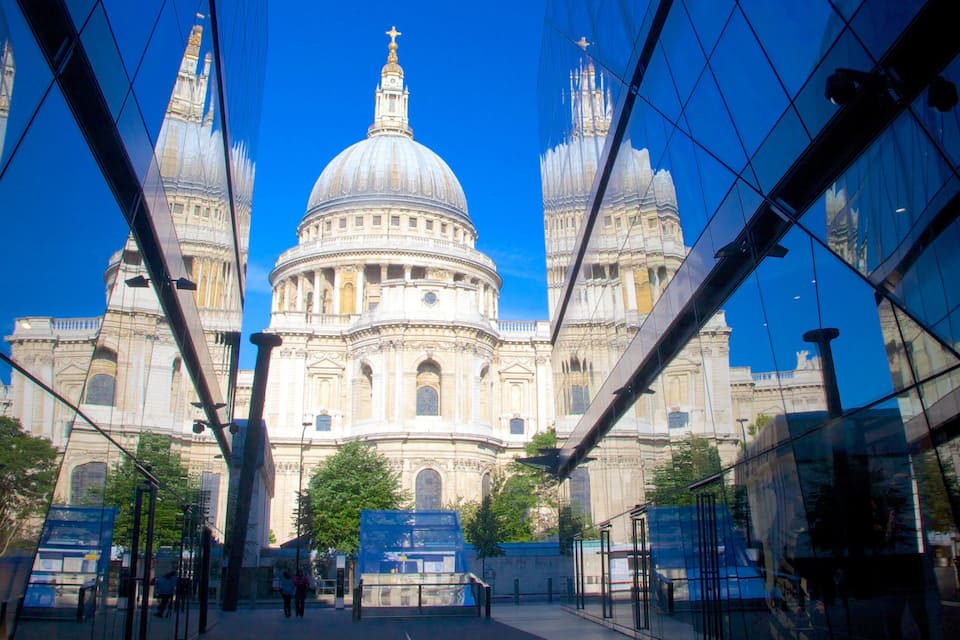 A large cathedral with a prominent dome and twin towers, surrounded by modern glass buildings.