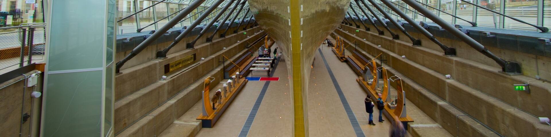 A large ship's bow inside a modern building with a glass roof.
