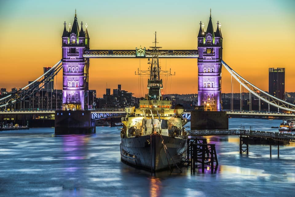 The Tower Bridge at sunset with a ship in the foreground.