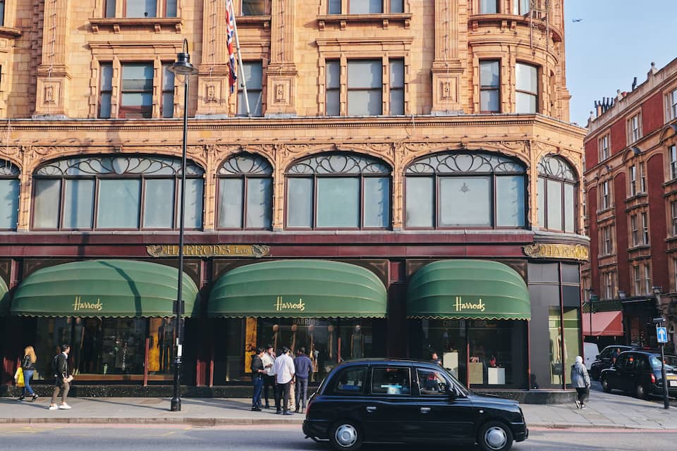 A historic building with ornate architecture and storefronts labeled 'Harrods'.