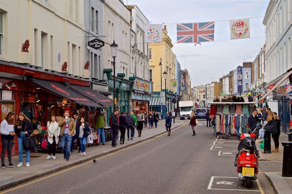 Une rue animée, bordée de boutiques, où l’on croise des piétons et où flotte un drapeau Union Jack.