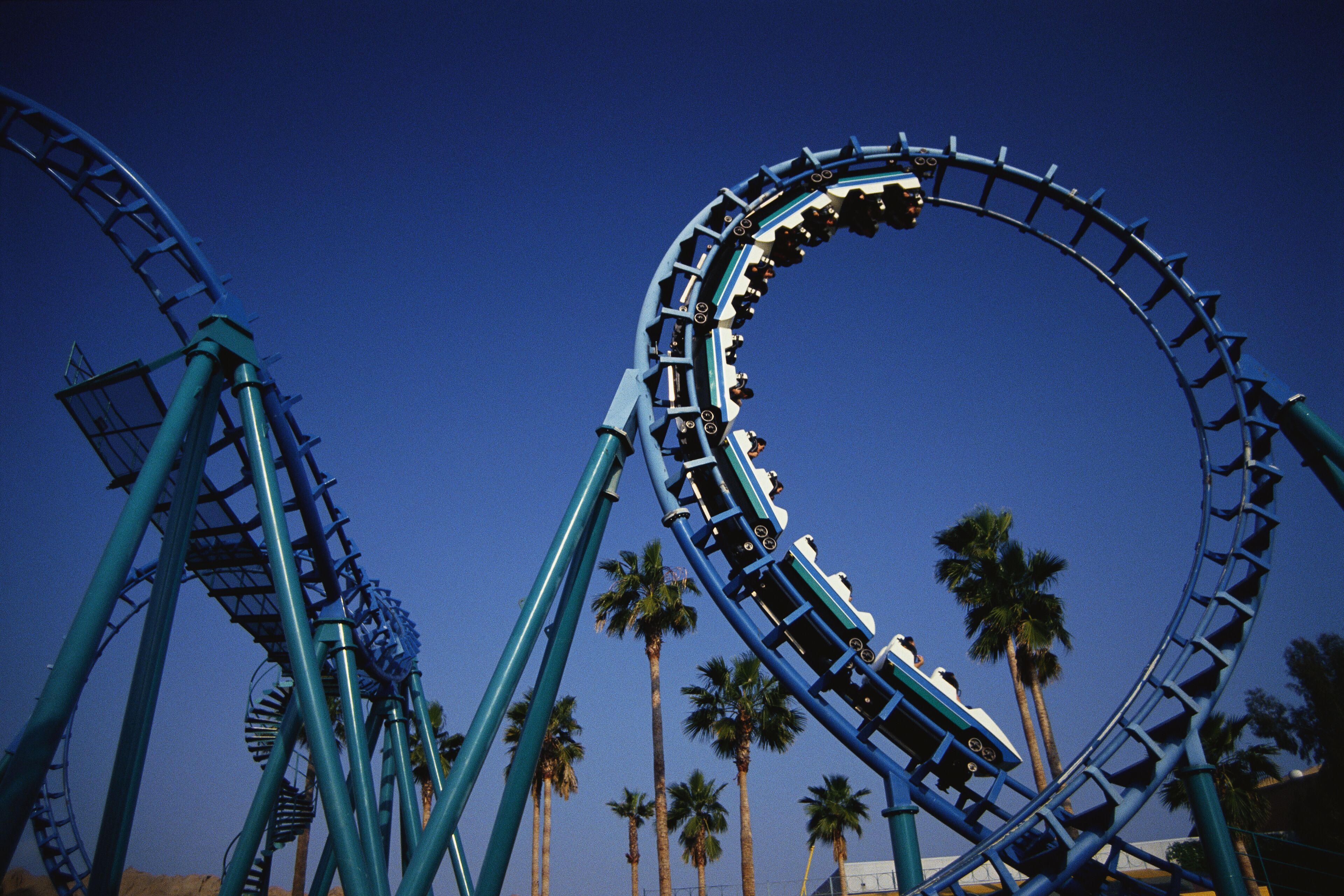 A roller coaster with a circular track, surrounded by palm trees.