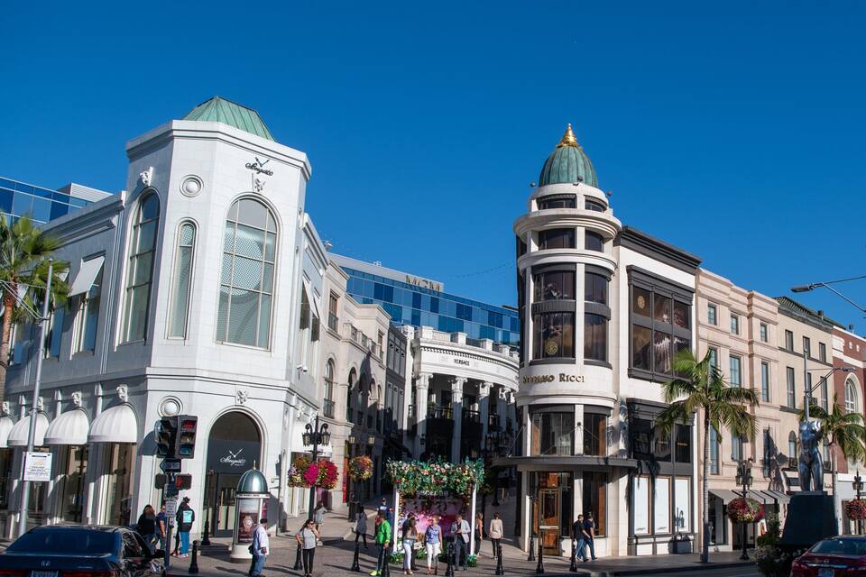A busy urban street with historic buildings, including a prominent white building with a green dome and another with a curved facade.