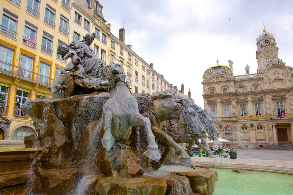 Una fuente con esculturas en una plaza, rodeada de edificios históricos.