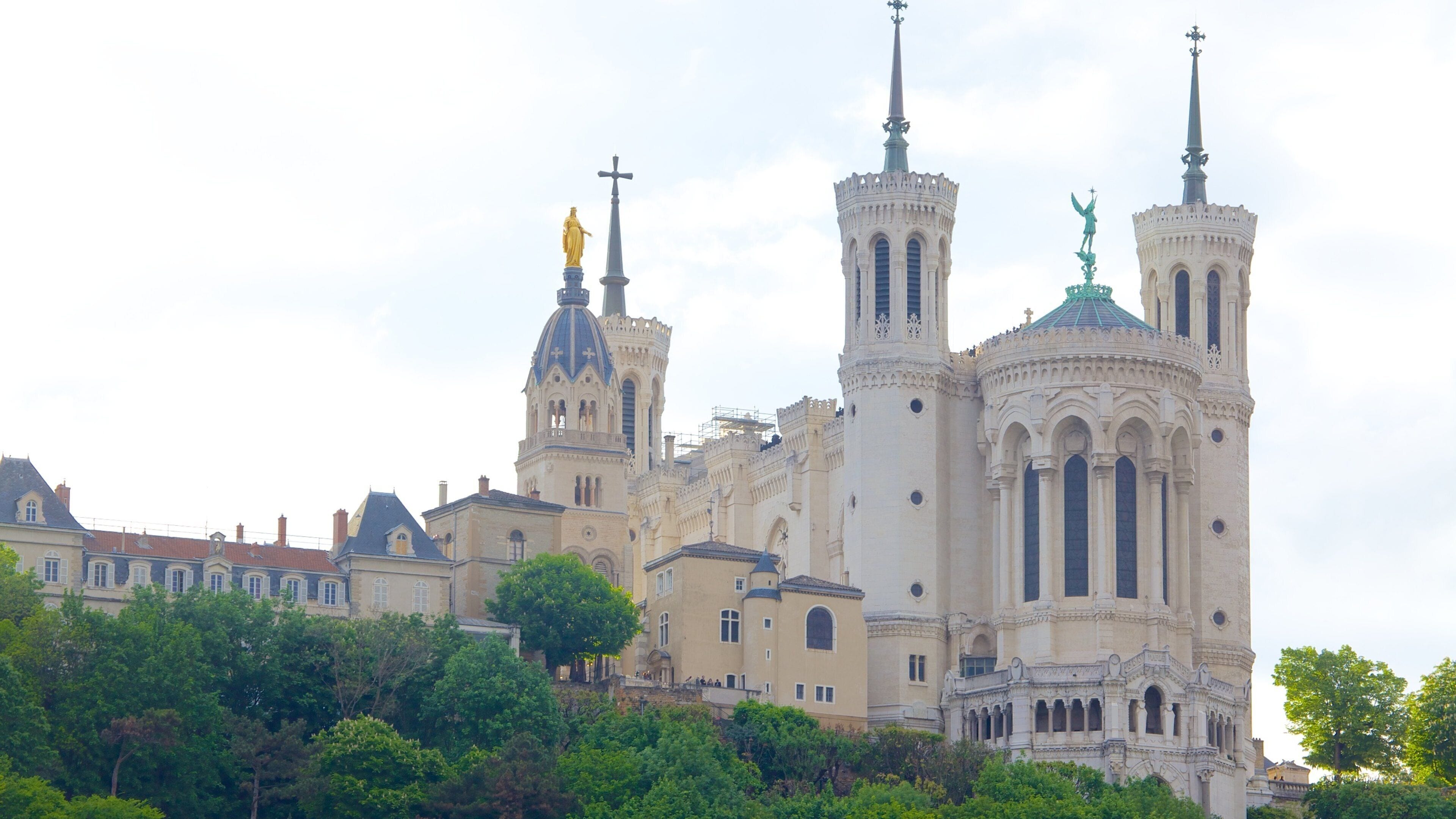 A historic cathedral with twin spires and statues, surrounded by lush greenery.