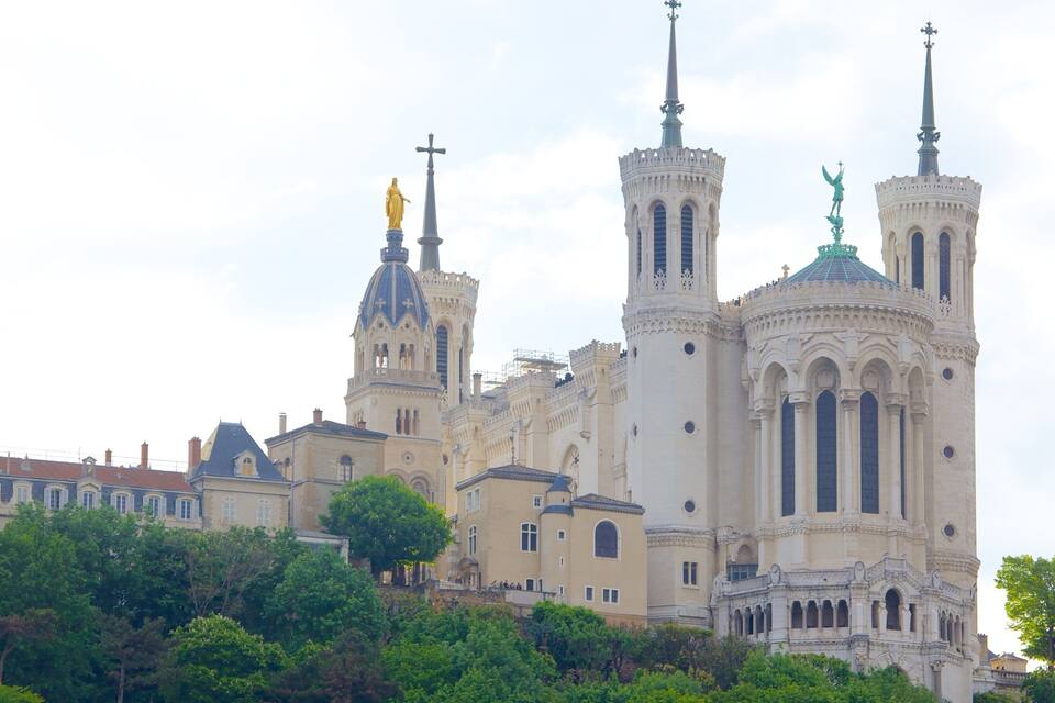A historic cathedral with twin spires and statues, surrounded by lush greenery.