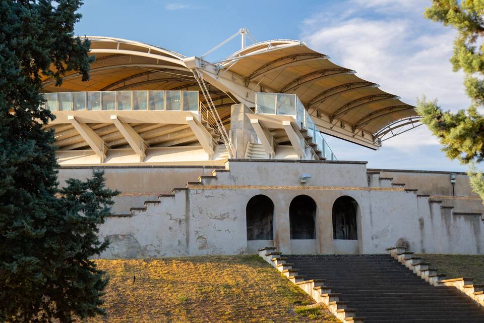 A modern architectural structure with a curved roof and a staircase leading up to it.