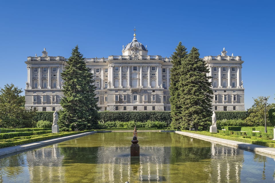 A grand palace with a symmetrical garden and a central fountain.