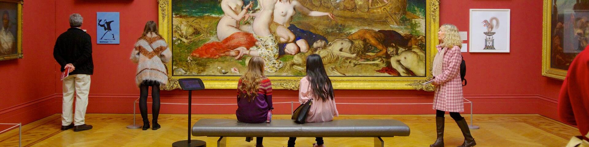 A large classical painting in a museum with red walls and golden frames.