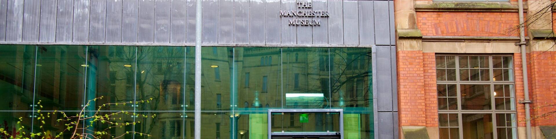 The entrance to The Manchester Museum with a modern glass facade and a traditional brick building to the right.