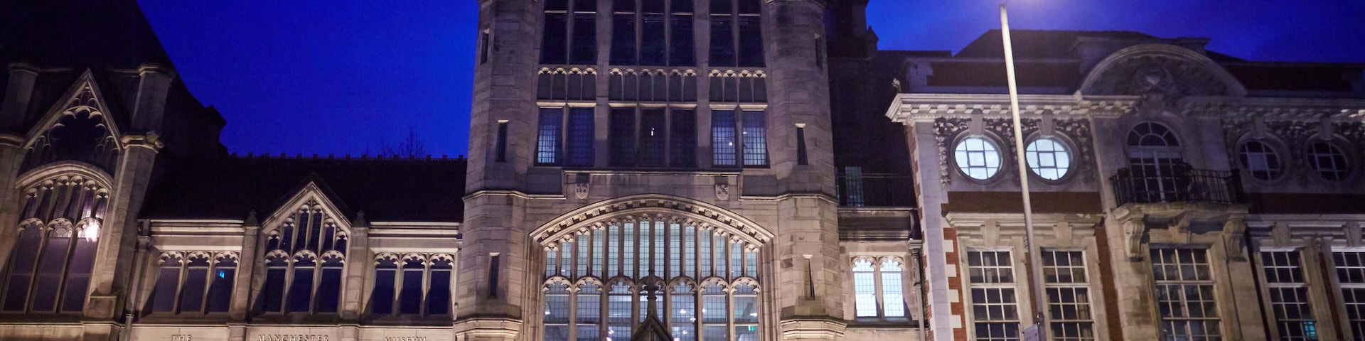 Um edifício histórico com arquitetura gótica, grandes janelas em arco e uma entrada imponente.