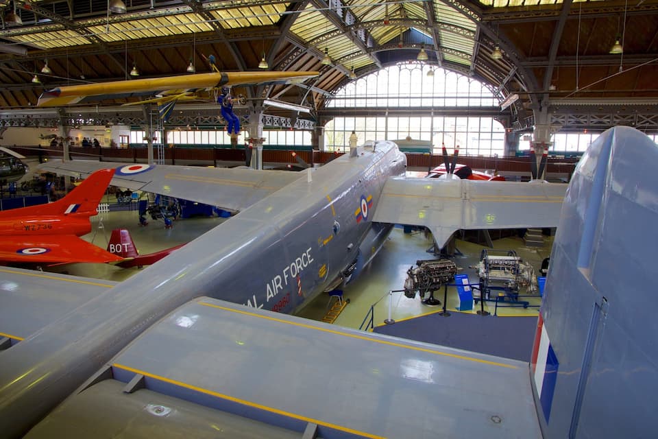 A large hangar with multiple aircraft, including a red fighter jet and a grey bomber.