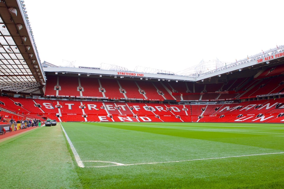 Un stade de football avec des sièges rouges et un terrain vert.