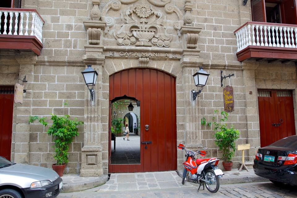 Um edifício histórico com uma porta vermelha, paredes de pedra e uma placa que diz 'Casa Manila Museum'.