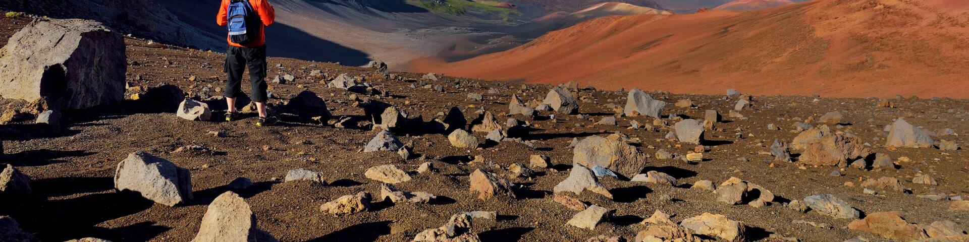 Tourist hiking in Haleakala volcano crater on the Sliding Sands trail. Beautiful view of the crater floor and the cinder cones below. Maui, Hawaii