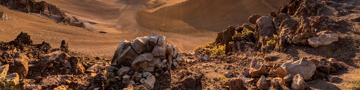 A mountainous landscape with a sunlit valley and rocky terrain.