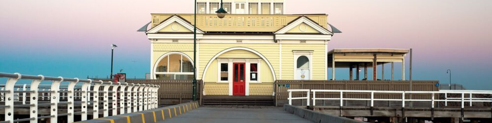 A pier with a building featuring a red door and a flag on top.