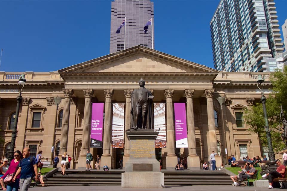 Un bâtiment de style classique, orné de colonnes, d’une statue et de bannières.