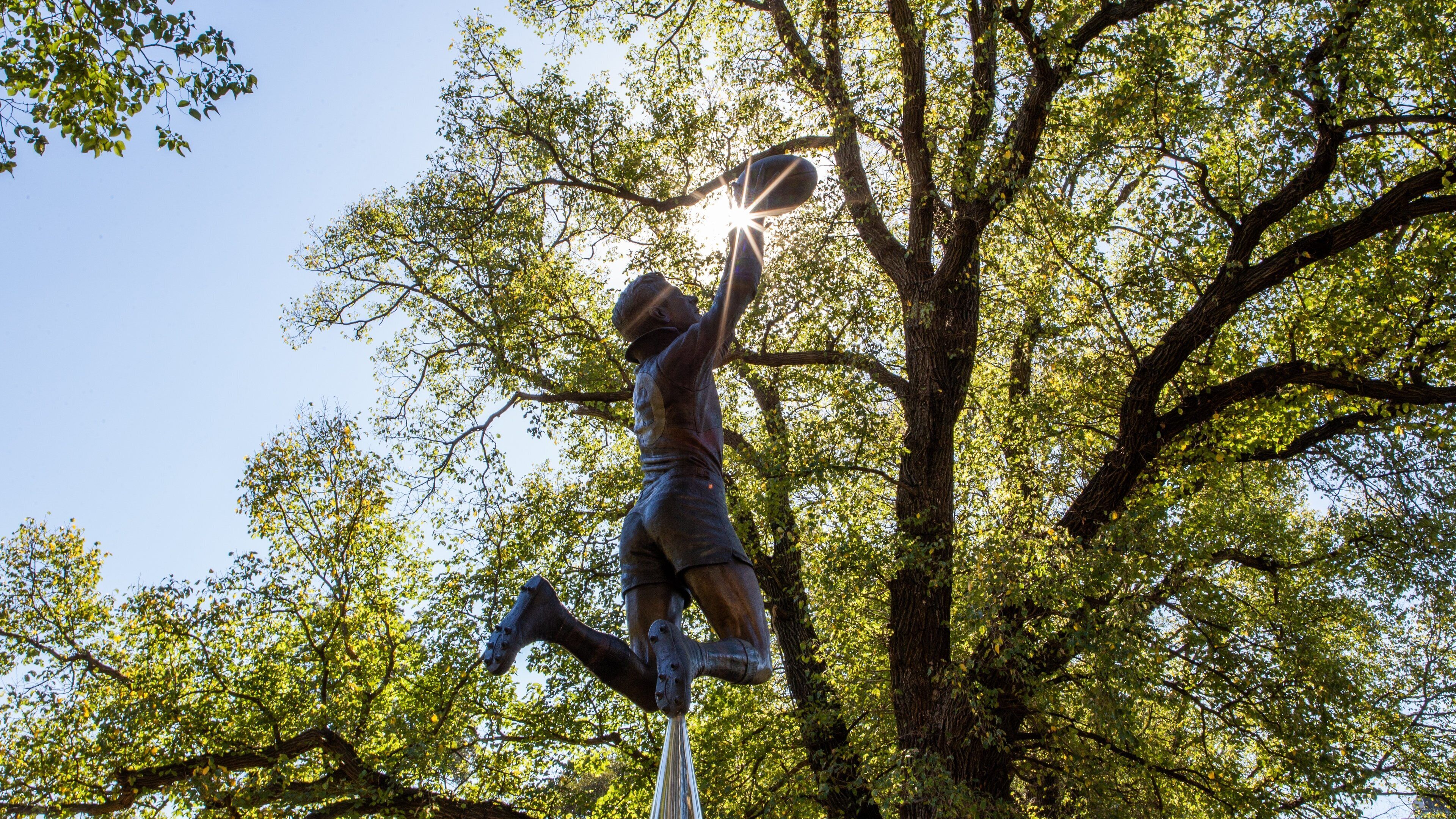 Melbourne Cricket Ground showing a statue or sculpture and a sunset