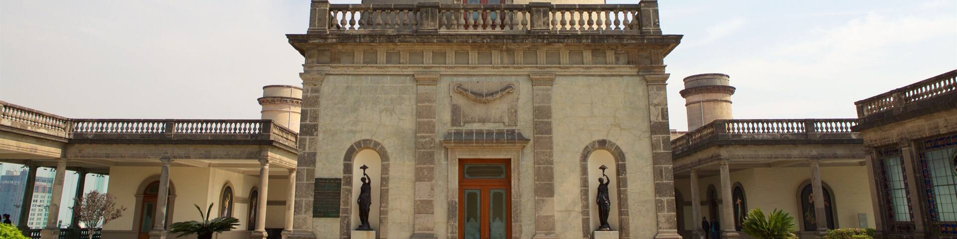 A historic building with a central tower, arched windows, and statues.
