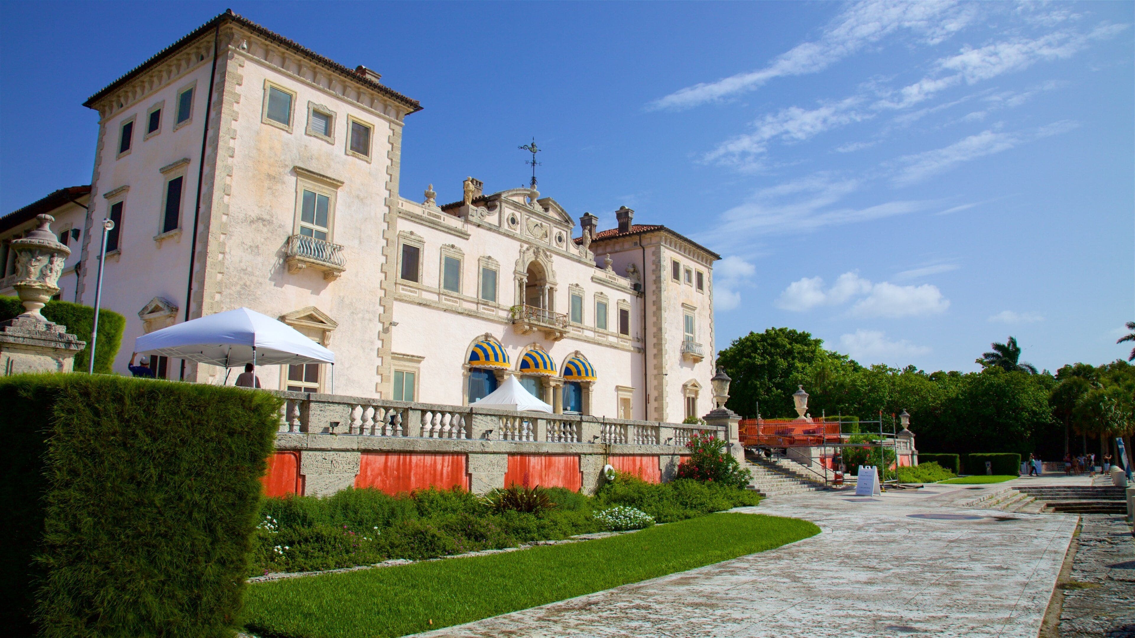 A historic building with a large balcony, a fountain, and a well-maintained garden.