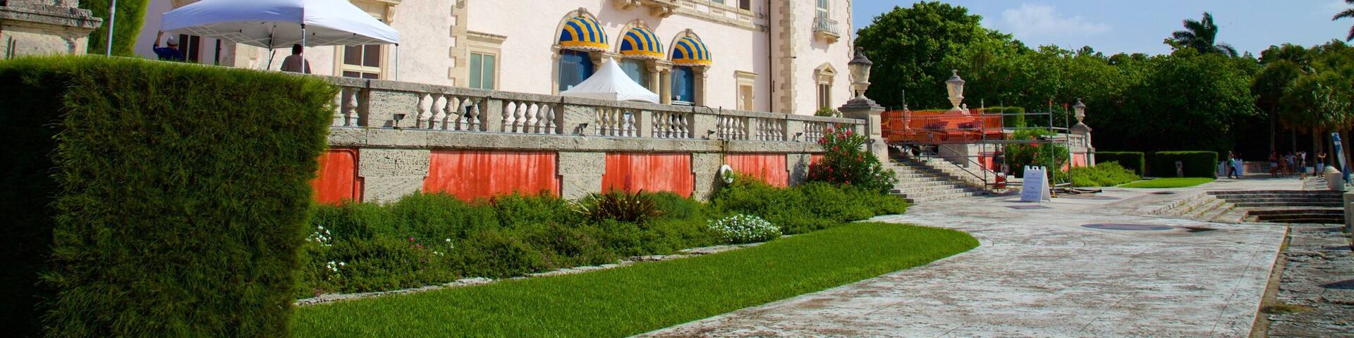A historic building with a large balcony, a fountain, and a well-maintained garden.