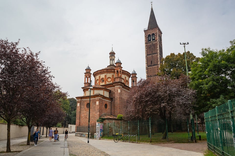 Una iglesia histórica con una alta torre campanario y una cúpula más pequeña.