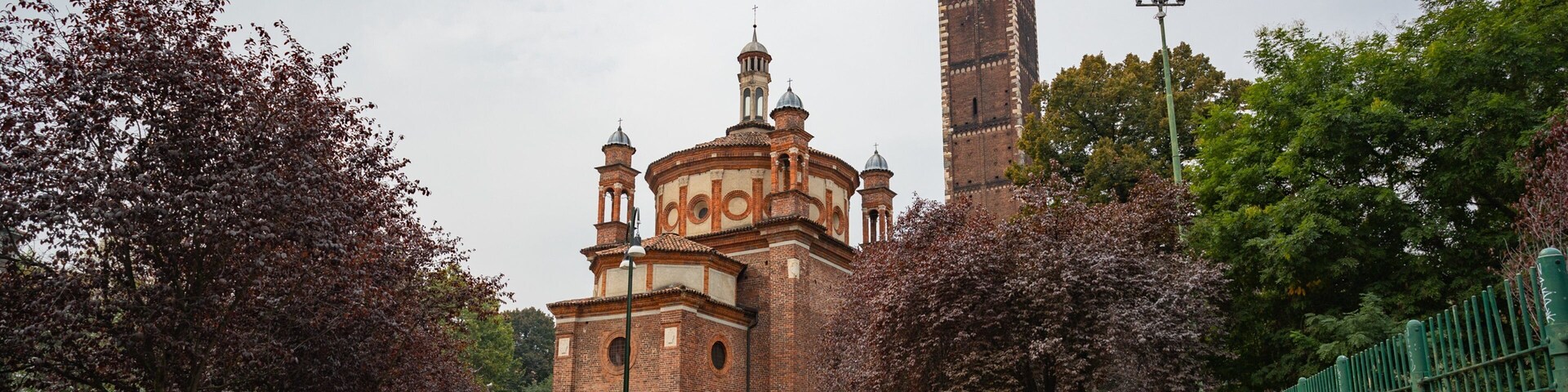 Una iglesia histórica con una alta torre campanario y una cúpula más pequeña.