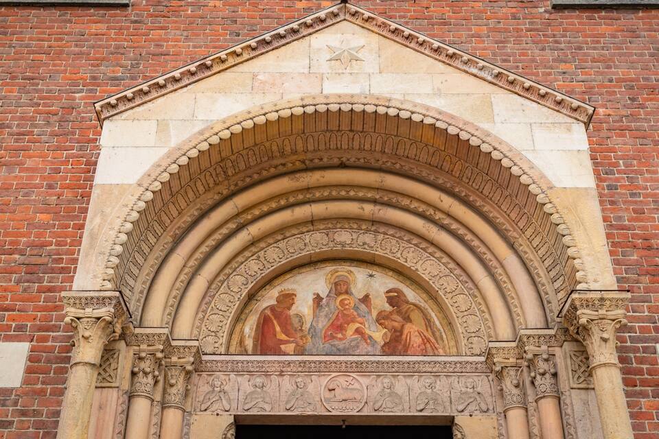 Un arco gotico con un affresco religioso e elaborate decorazioni in pietra.