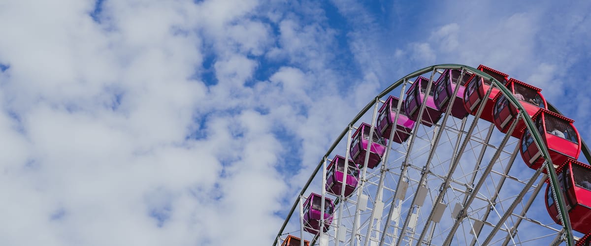 Negative space, artistic composition of a colorful large ferris wheel against a partly cloudy sky