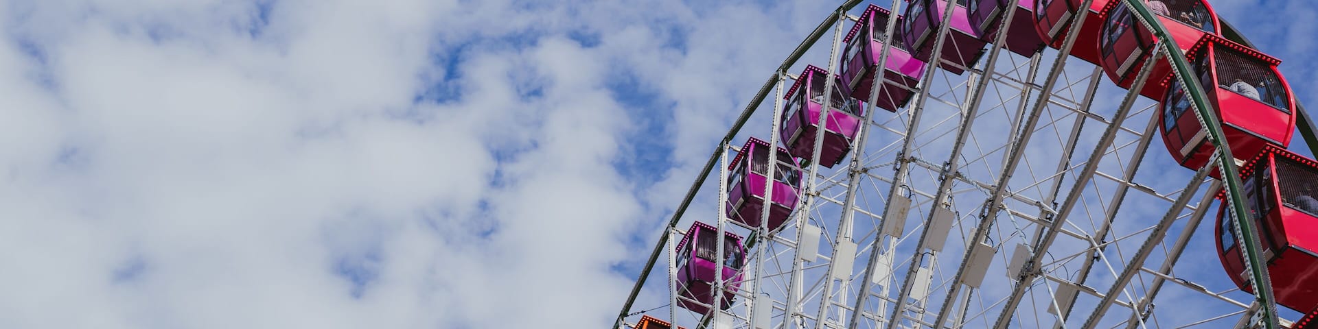 Negative space, artistic composition of a colorful large ferris wheel against a partly cloudy sky