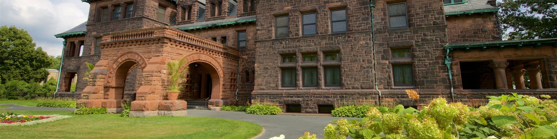 A large, historic stone building with multiple chimneys and green roofs.