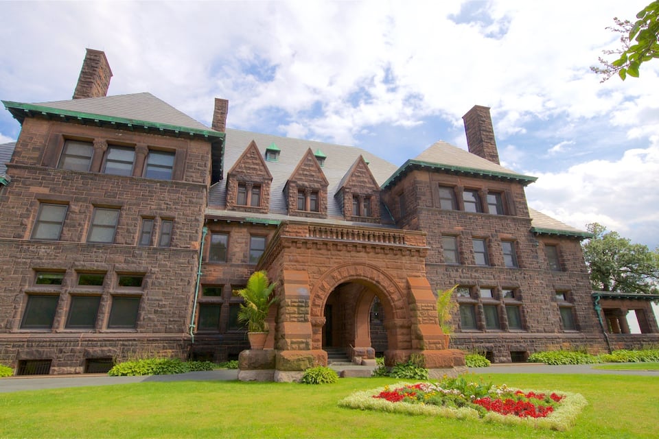 A large, historic stone building with a prominent archway and a green roof.