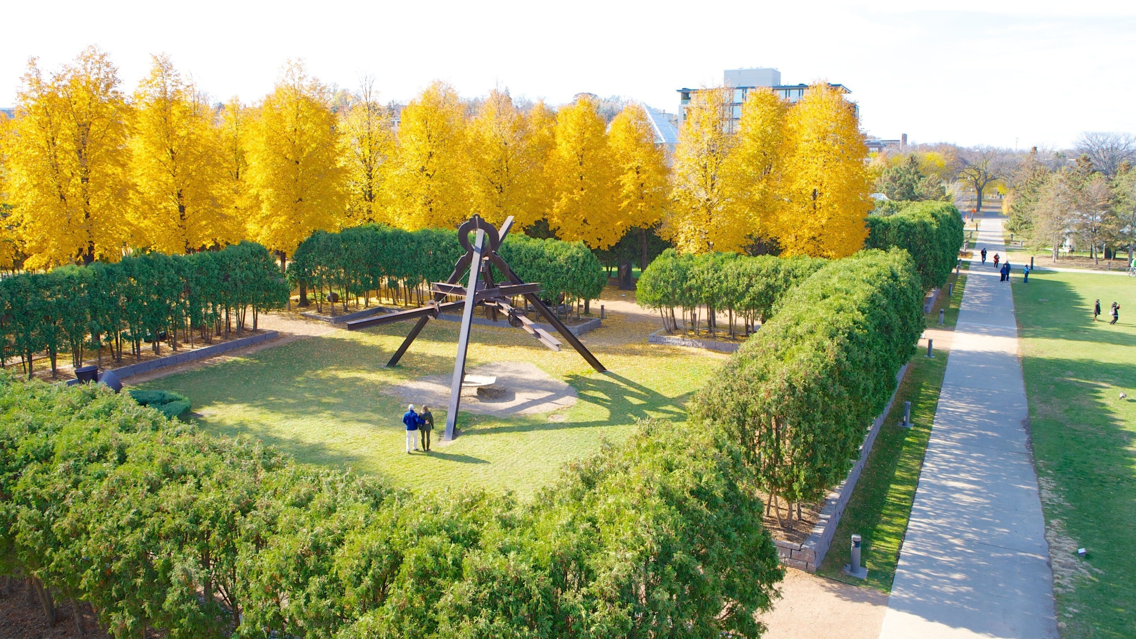 Um parque com árvores amarelas, um parquinho e uma trilha.