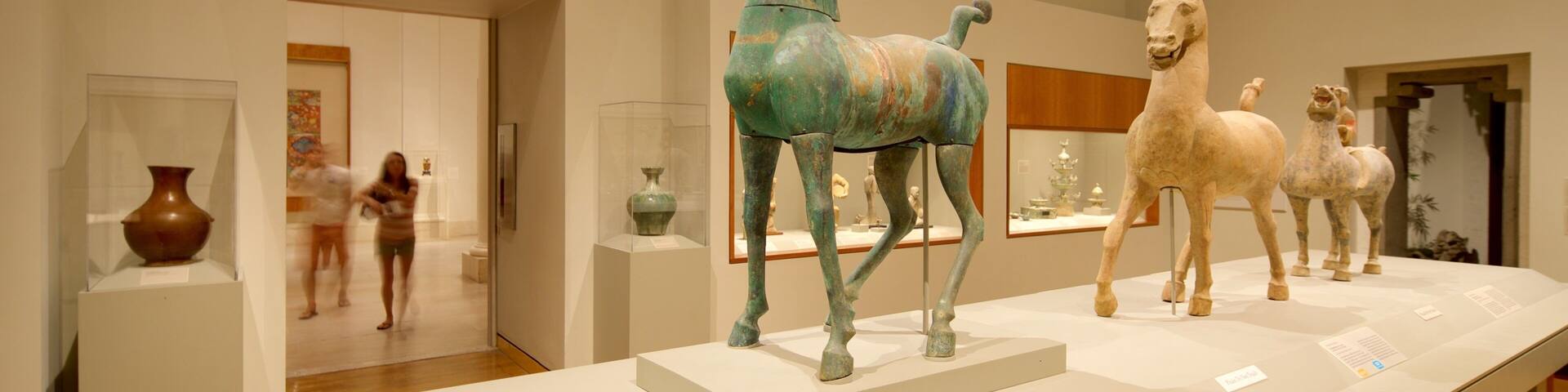 A museum exhibit with ancient horse statues and pottery.