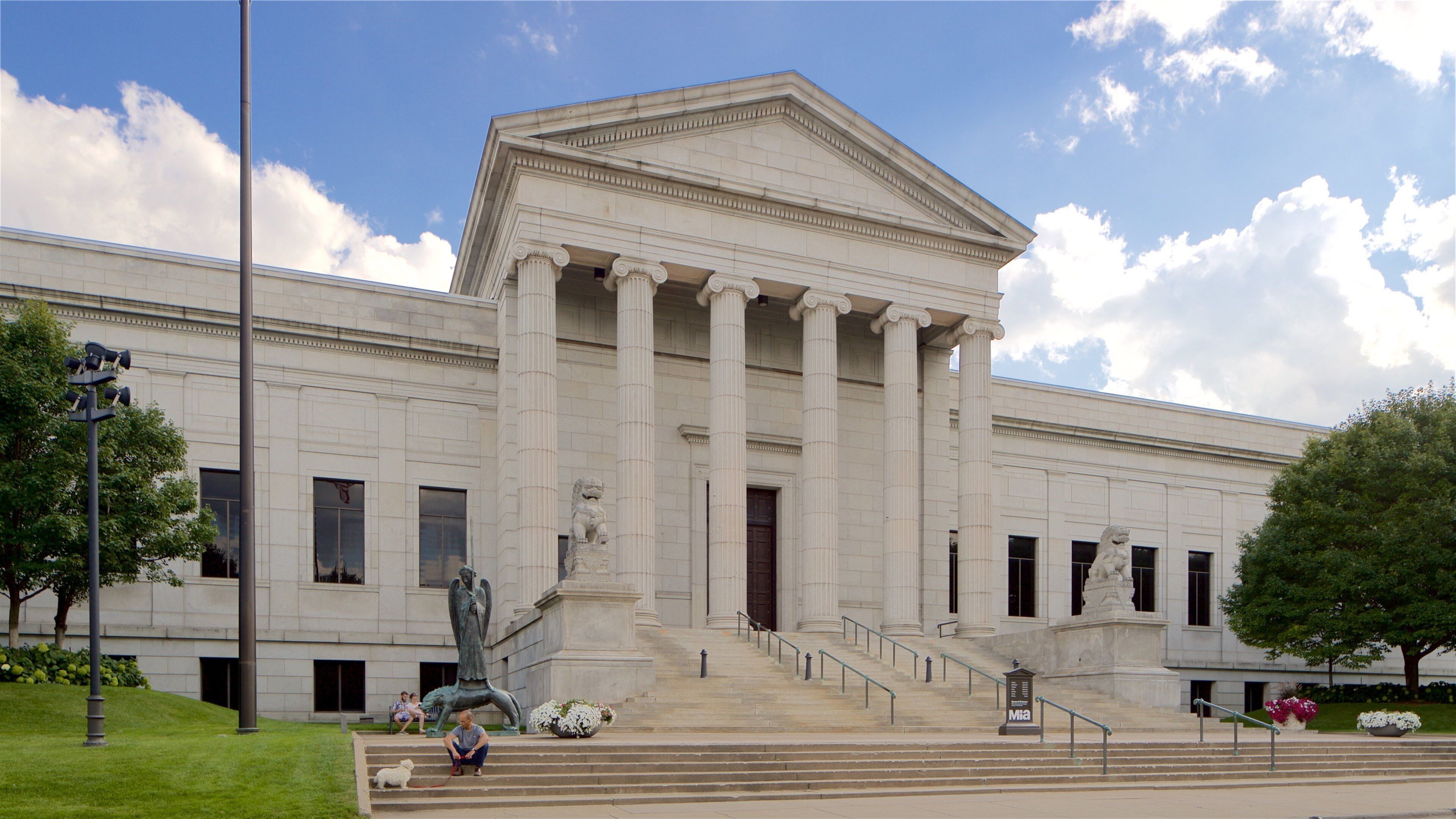 A neoclassical building with a grand entrance, large columns, and a statue.