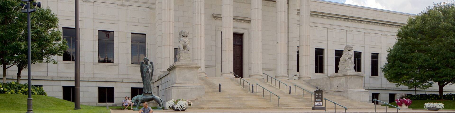 A neoclassical building with a grand entrance, large columns, and a statue.