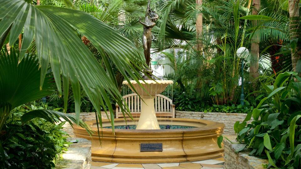A fountain with a statue, surrounded by lush tropical plants.