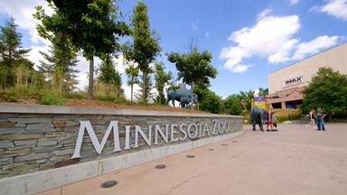 Entrada do Zoológico do Minnesota, com um muro de pedra, árvores e um cinema IMAX ao fundo.